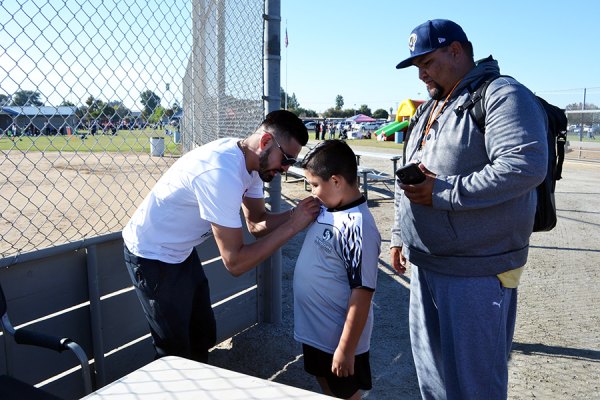 Avenal's Jose Ramirez, the WBC's Super Lightweight Champion, was on hand Saturday at the Lemoore Youth Sports Complex to watch family play and sign a few autographs. Here he signs for Max Gomez, 7, and father Alejandro Gomez.